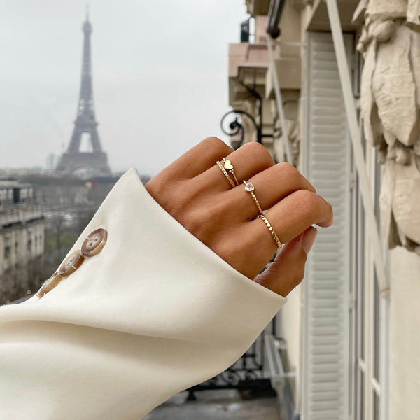 Hand wearing 24KAE JEWELS JEWELRY Mod. 12417S/54 near Eiffel Tower, showcasing elegant gold rings