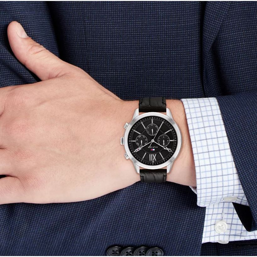 Gent wearing TOMMY HILFIGER Mod. 1710527 multifunction quartz watch, black bracelet, 44mm case, 5 ATM water resistant, mineral dial.