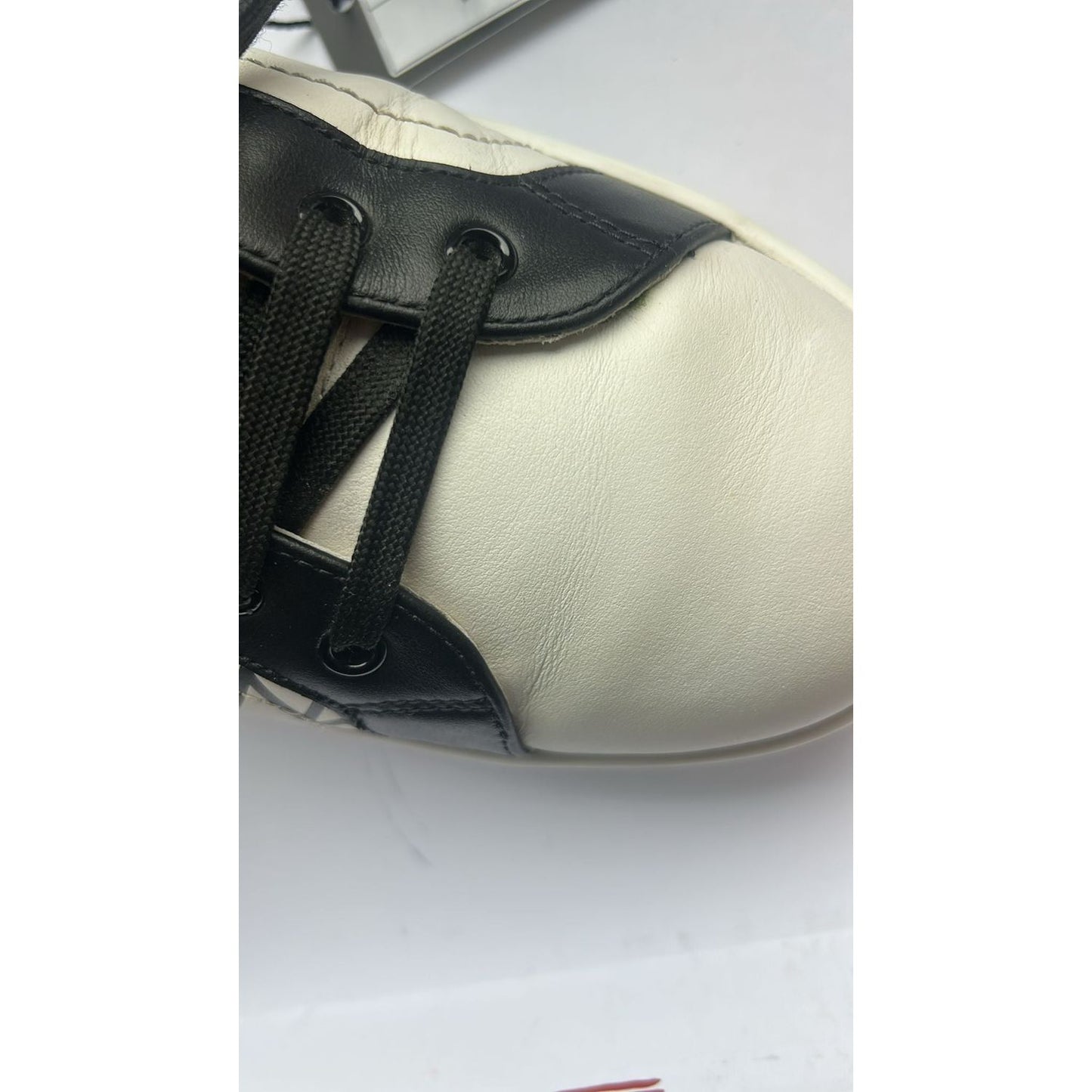 Close-up of Dolce & Gabbana white black leather low-top sneakers showcasing lacing and texture details.