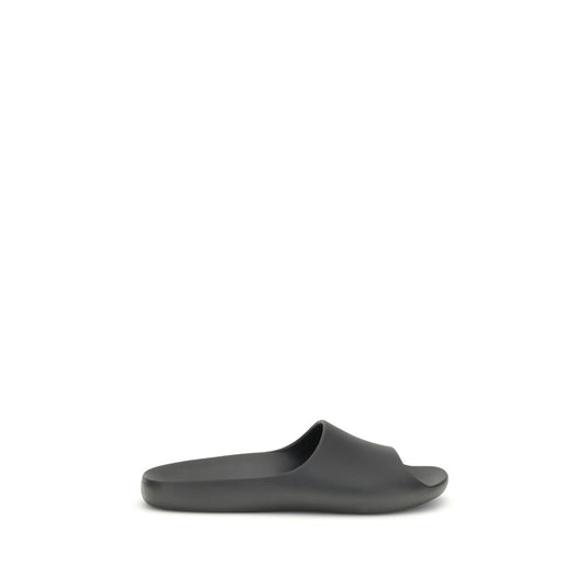 The Row Black Rubber Slippers featuring minimalistic design with contoured footbed for comfort, seamless construction, and lightweight feel.