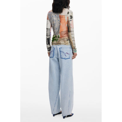 Model wearing Desigual Beige Viscose Women Top with eye-catching pattern, paired with light blue jeans, showcasing stylish fashion flair.